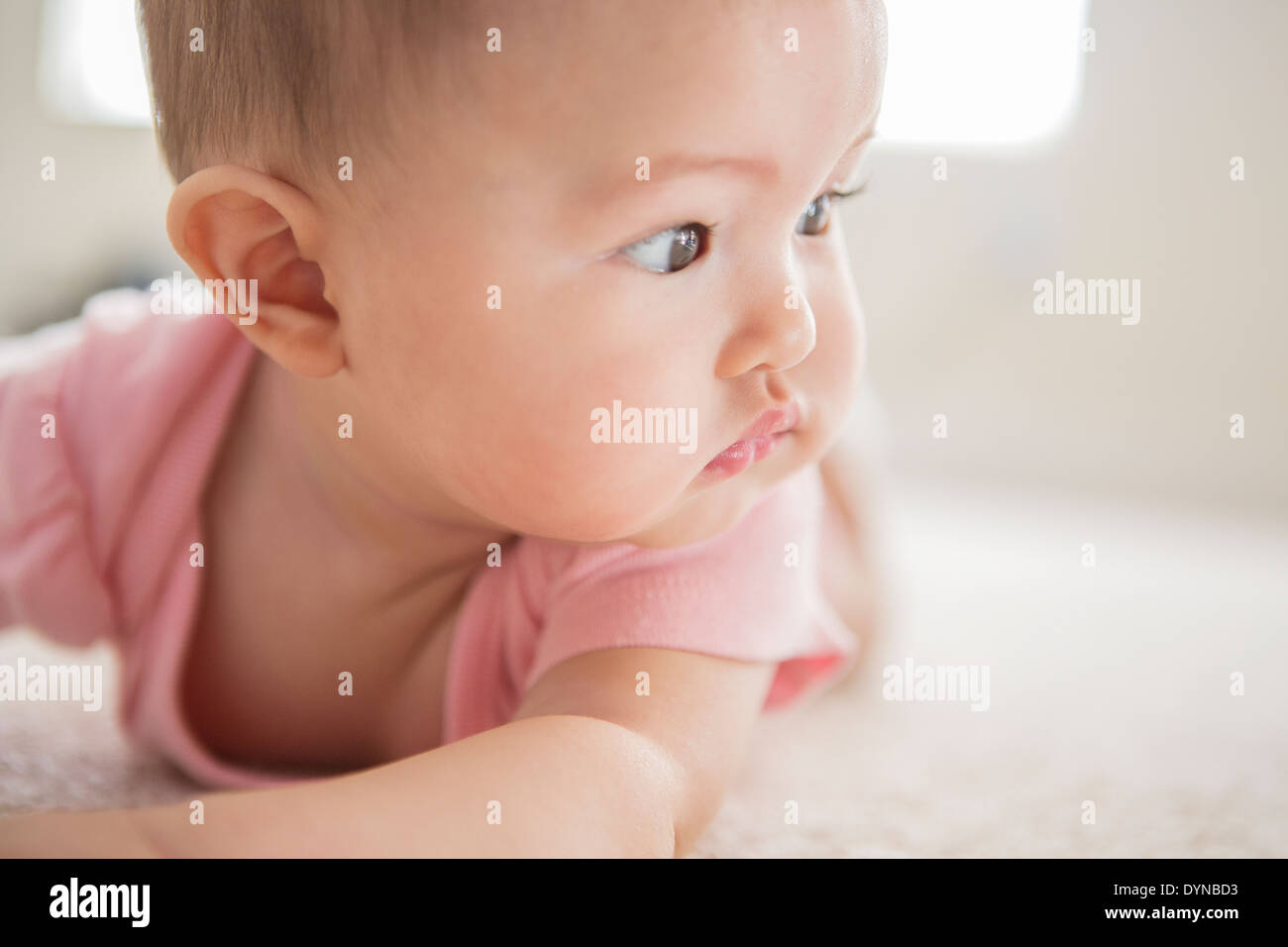 Mixed race baby girl laying on carpet Stock Photo