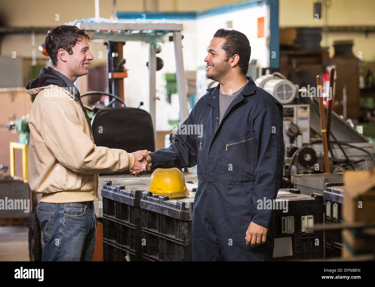 Workers shaking hands in warehouse Stock Photo