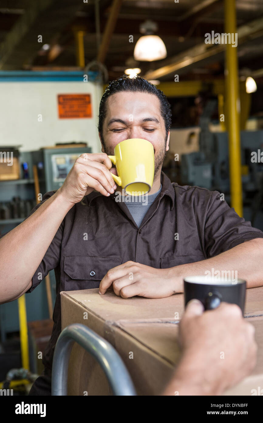 Worker drinking coffee in warehouse Stock Photo