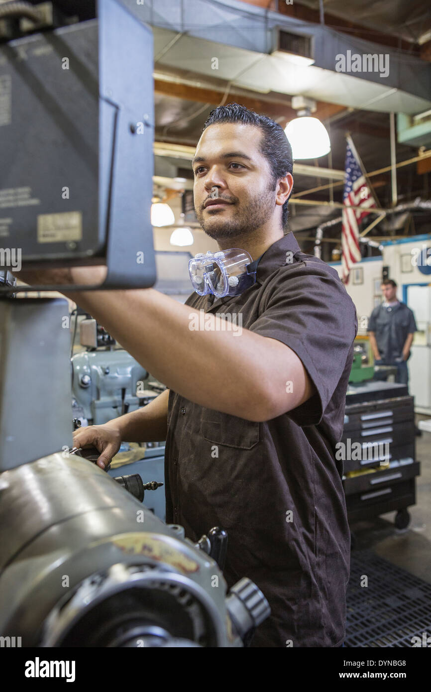 Hispanic worker operating machinery in factory Stock Photo