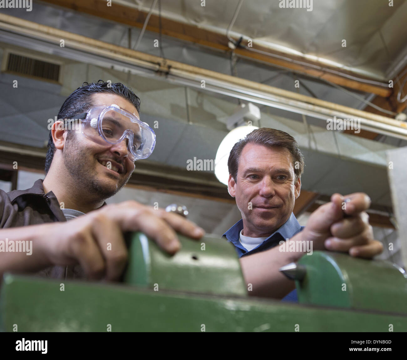 Worker and manager examining machinery in factory Stock Photo