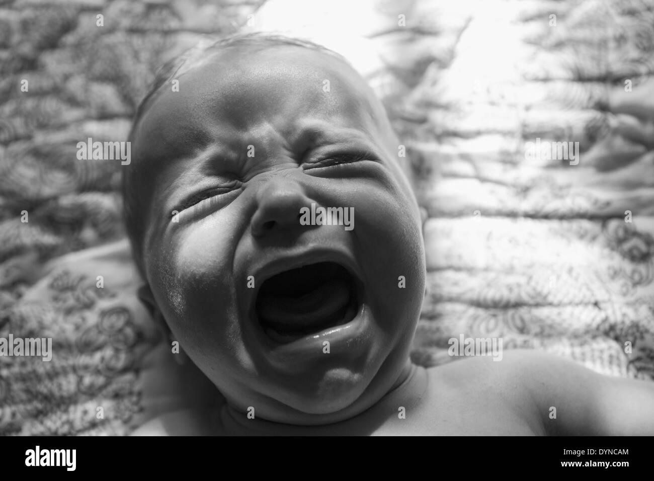 Caucasian baby crying on bed Stock Photo