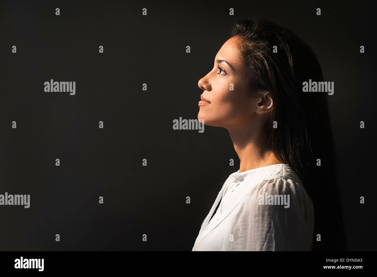 Hispanic woman looking up into light Stock Photo