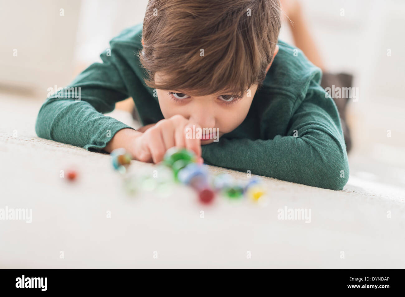 Hispanic boy playing with marbles on bedroom floor Stock Photo