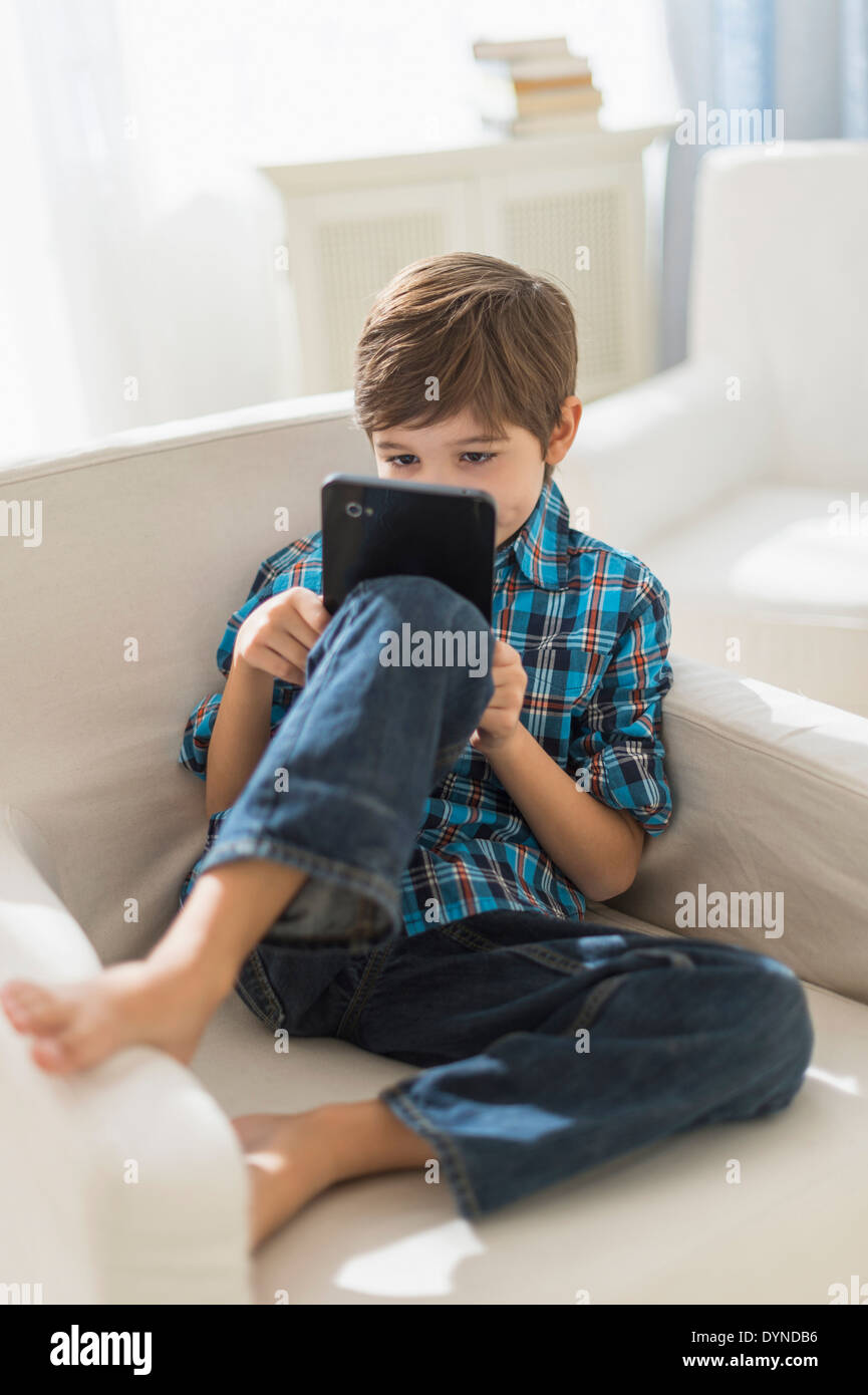 Hispanic boy using digital tablet in armchair Stock Photo