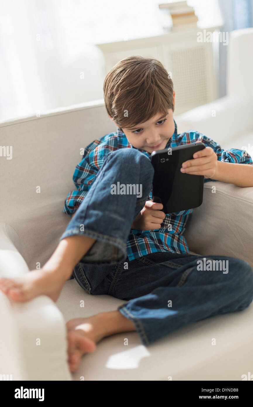 Hispanic boy using digital tablet in armchair Stock Photo