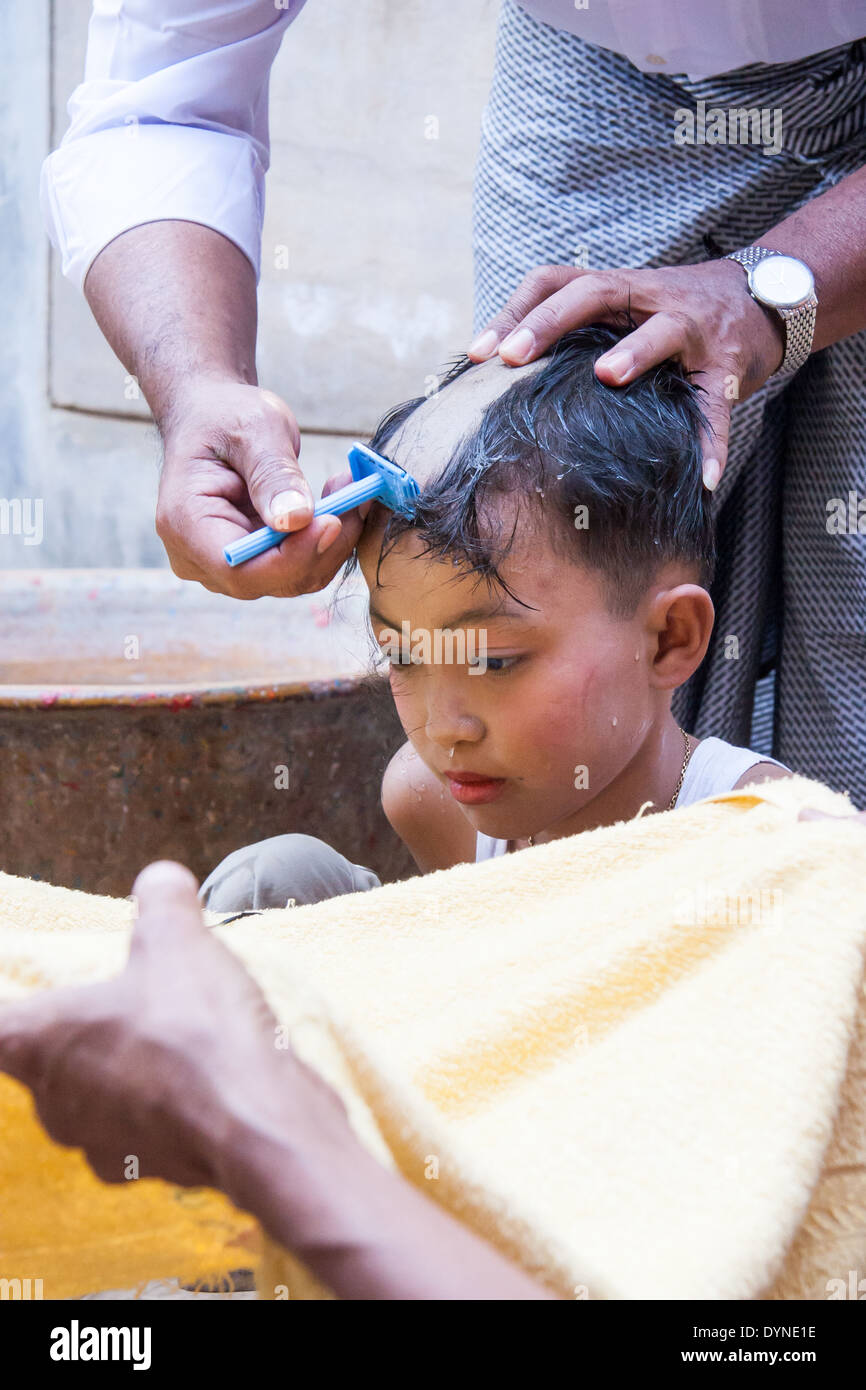 Young boy having his head shaved on the day he becomes a monk Stock Photo