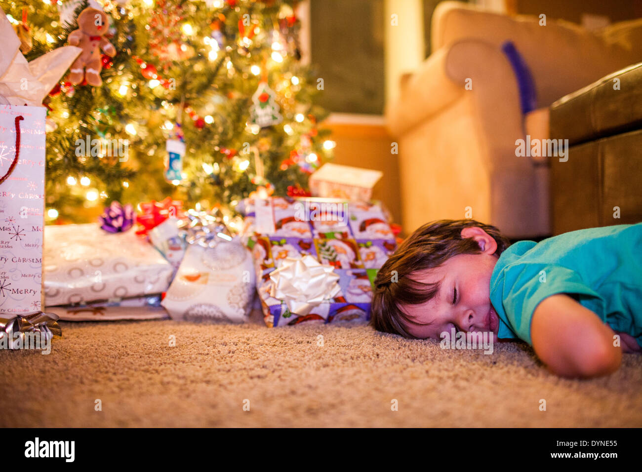 Caucasian boy sleeping by Christmas gifts Stock Photo