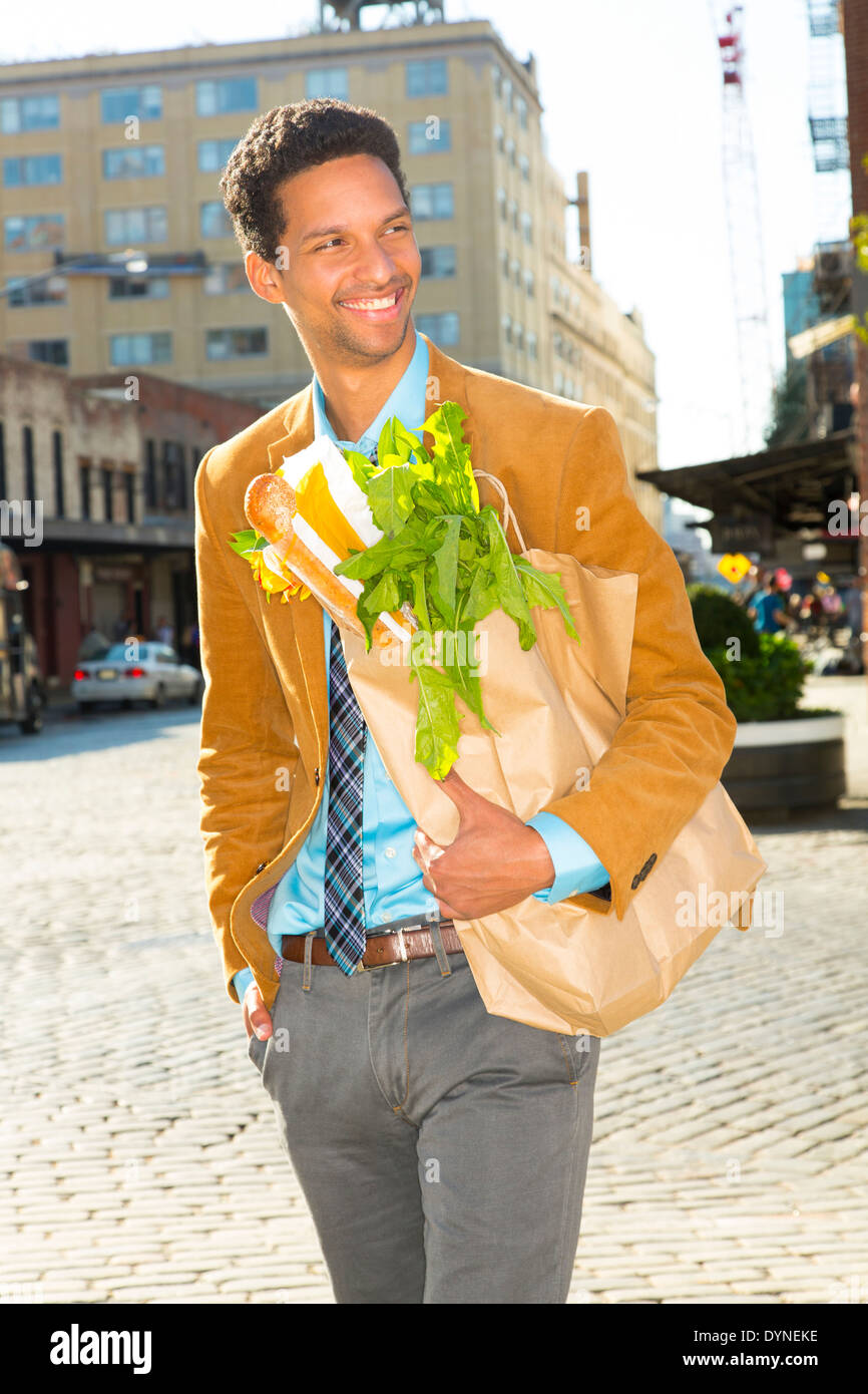 Mixed race businessman with groceries on city street Stock Photo