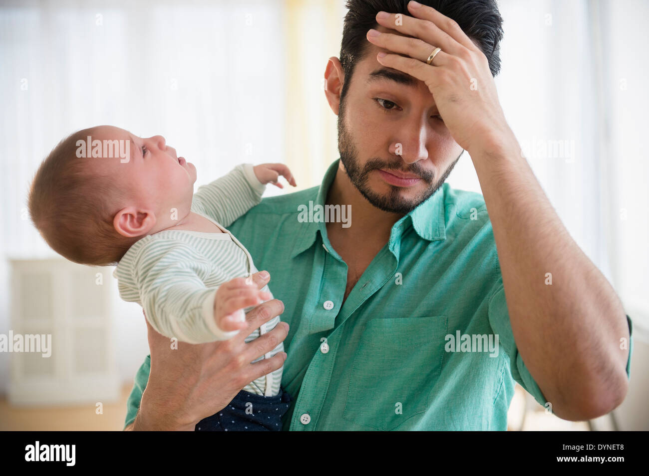 Frustrated father holding crying baby Stock Photo