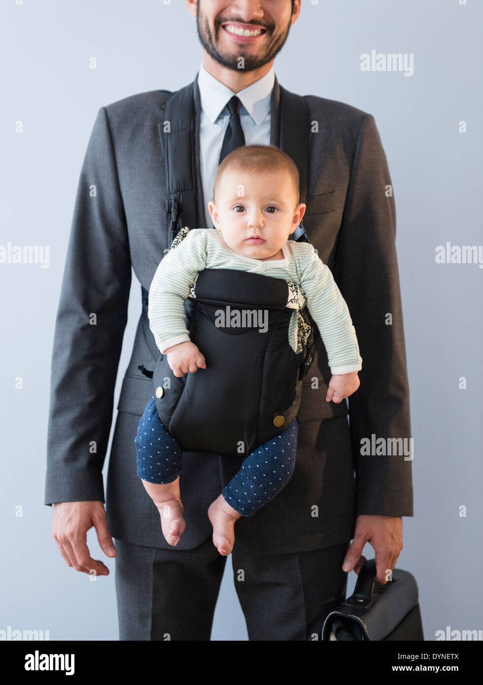 Businessman carrying baby in carrier Stock Photo