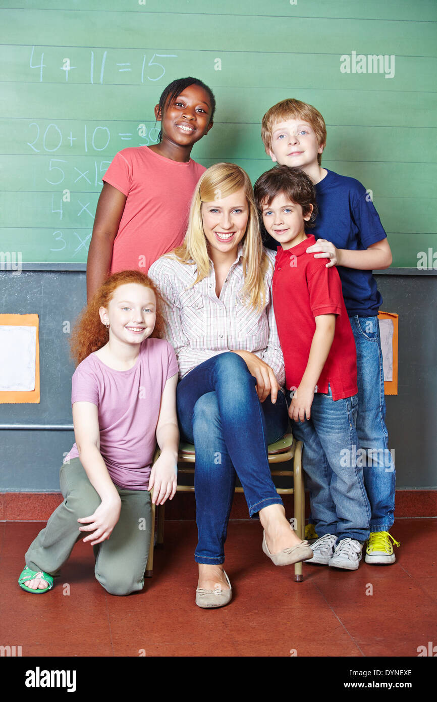 Happy teacher and students in elementary school in front of a chalkboard Stock Photo