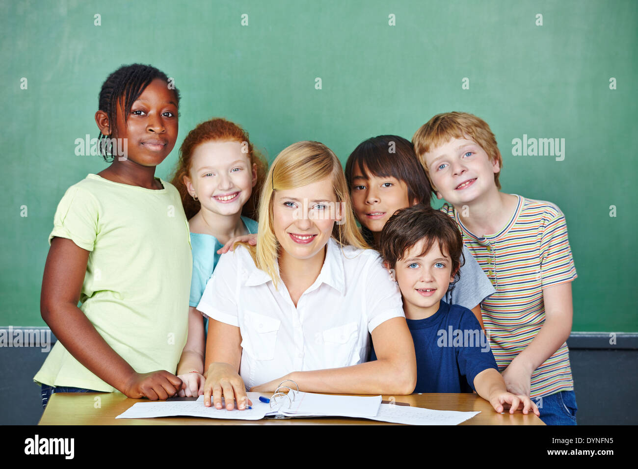 Portrait of happy teacher with group of students in front of chalkboard Stock Photo