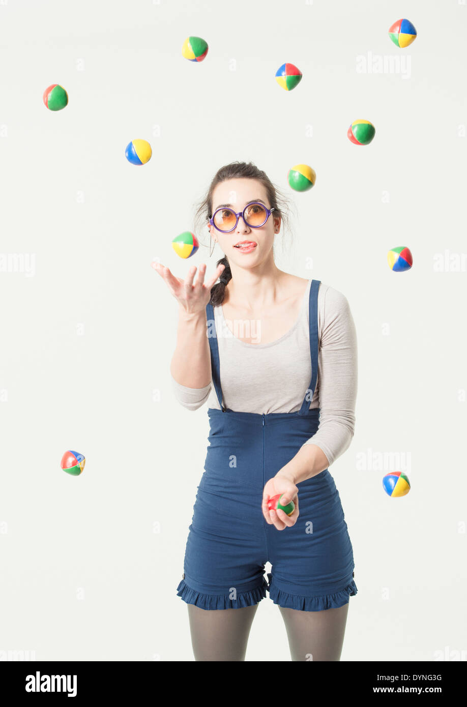 Concentrated young hispanic woman with glasses juggling with many balls Stock Photo