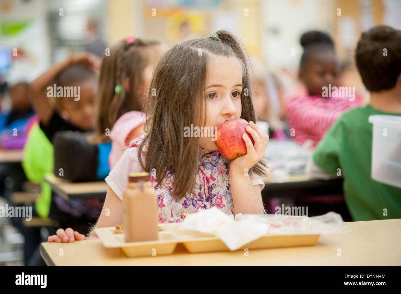 Girl biting into apple in school cafeteria Hagerstown, Maryland Stock Photo