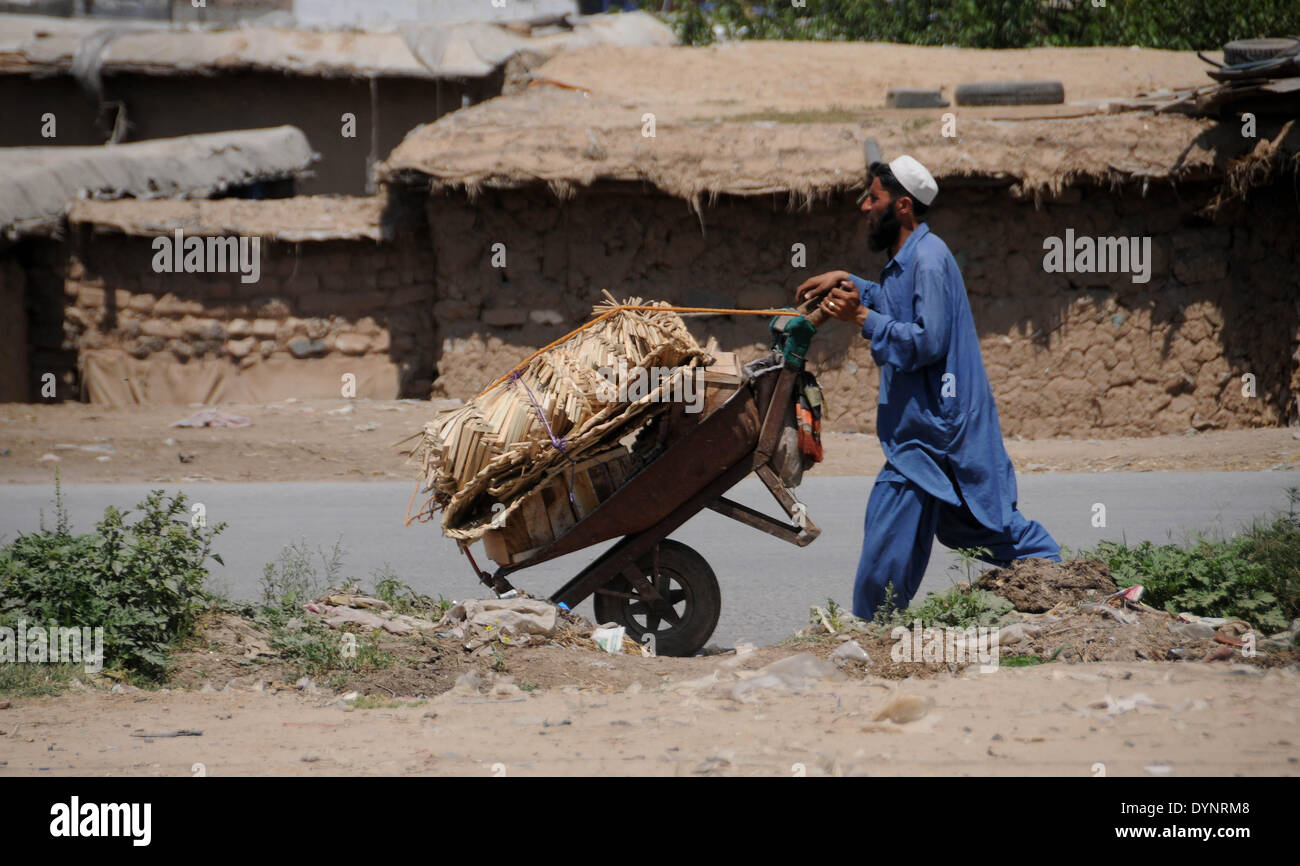 ISLAMABAD, PAKISTAN-APRIL 23: An Afghan refugee carries mats which are to be used for prayers on his wheelbarrow in the slum area in the outskirts of Islamabad, Pakistan. More than five millions of Afghan refugees fled their homeland since Soviet invasion in 1970s. Some 3.6 million Afghan refugees have been repatriated to Afghanistan from Pakistan since March 2002, under a tripartite agreement between the UN Refugee Agency (UNHCR) and the governments of Pakistan and Afghanistan. More than 1.6 million Afghan refugees are still living in Pakistan, especially in camps and slums areas and not retu Stock Photo