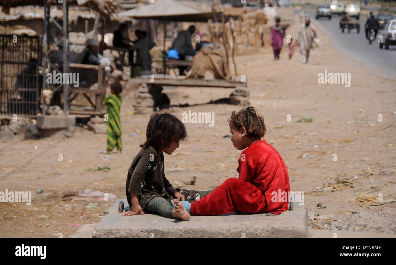 ISLAMABAD, PAKISTAN-APRIL 23: Afghan refugee children play as others walk in the slum area in the outskirts of Islamabad, Pakistan. More than five millions of Afghan refugees fled their homeland since Soviet invasion in 1970s. Some 3.6 million Afghan refugees have been repatriated to Afghanistan from Pakistan since March 2002, under a tripartite agreement between the UN Refugee Agency (UNHCR) and the governments of Pakistan and Afghanistan. More than 1.6 million Afghan refugees are still living in Pakistan, especially in camps and slums areas and not returning to their homeland due to continue Stock Photo