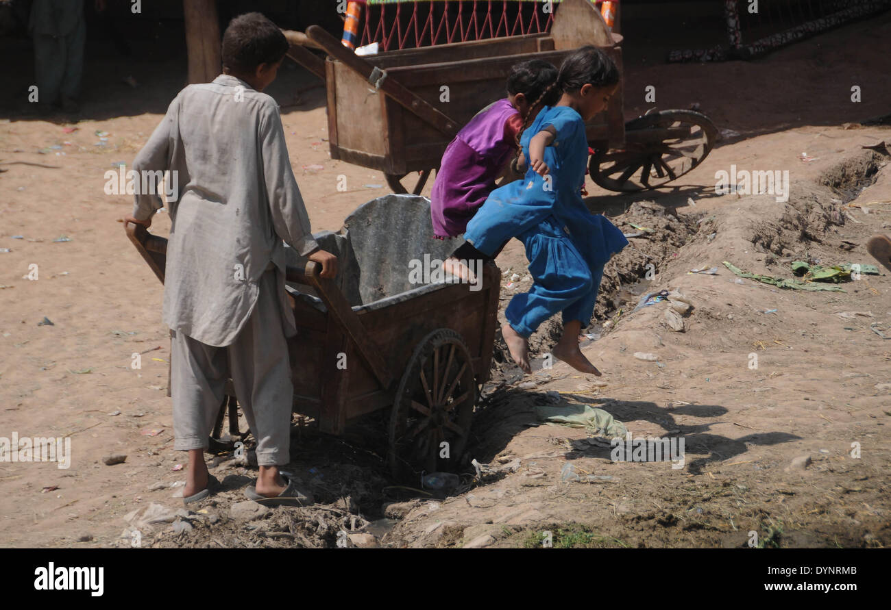ISLAMABAD, PAKISTAN-APRIL 23: Afghan refugee girls play as a boy pushes his hand cart in the slum area in the outskirts of Islamabad, Pakistan. More than five millions of Afghan refugees fled their homeland since Soviet invasion in 1970s. Some 3.6 million Afghan refugees have been repatriated to Afghanistan from Pakistan since March 2002, under a tripartite agreement between the UN Refugee Agency (UNHCR) and the governments of Pakistan and Afghanistan. More than 1.6 million Afghan refugees are still living in Pakistan, especially in camps and slums areas and not returning to their homeland due Stock Photo