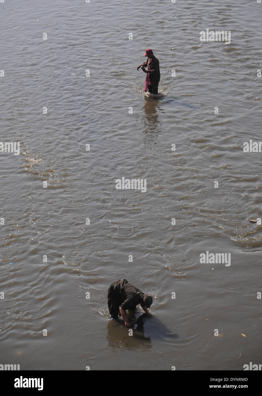 ISLAMABAD, PAKISTAN-APRIL 23: Afghan refugee search for iron items using magnetic in the dirty water of a stream passing through the main market in the slum area in the outskirts of Islamabad, Pakistan. More than five millions of Afghan refugees fled their homeland since Soviet invasion in 1970s. Some 3.6 million Afghan refugees have been repatriated to Afghanistan from Pakistan since March 2002, under a tripartite agreement between the UN Refugee Agency (UNHCR) and the governments of Pakistan and Afghanistan. More than 1.6 million Afghan refugees are still living in Pakistan, especially in ca Stock Photo