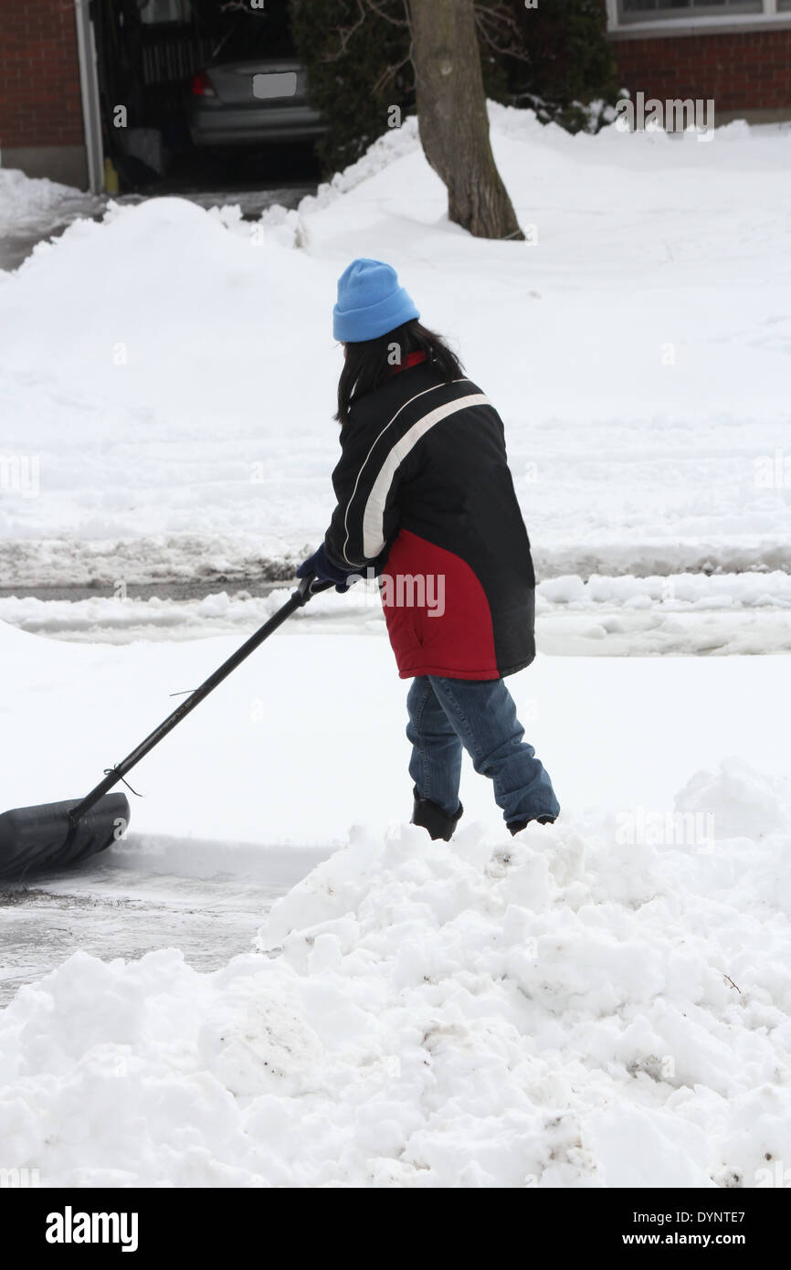 Lady shoveling the deep snow off her driveway after a snow storm. Stock Photo