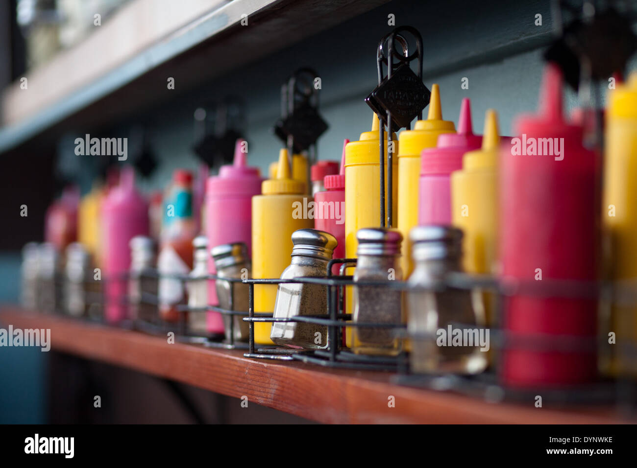 Spices, ketchup and mustard containers are lined up at a fast food