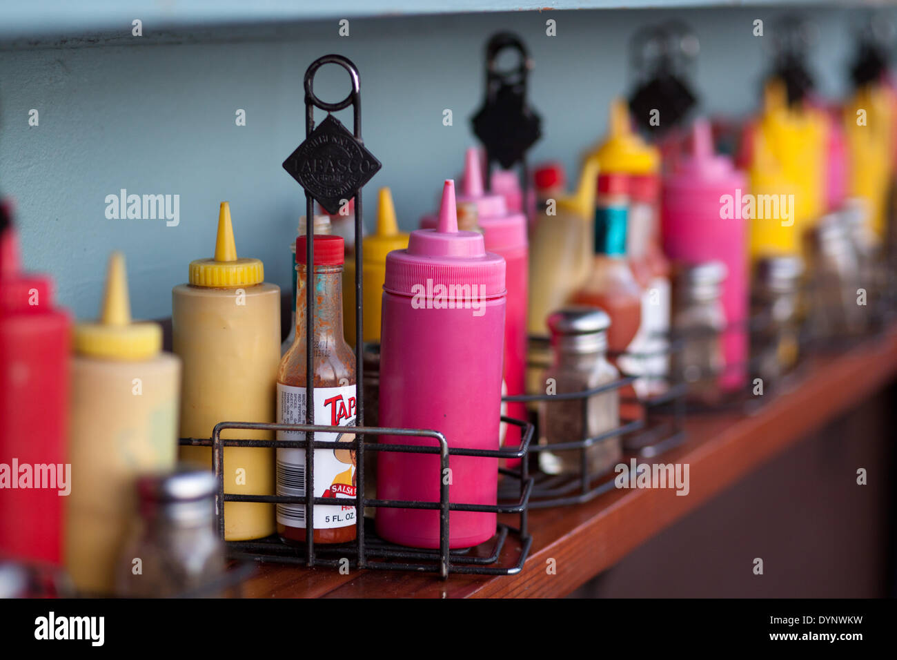 Spices, ketchup and mustard containers are lined up at a fast food