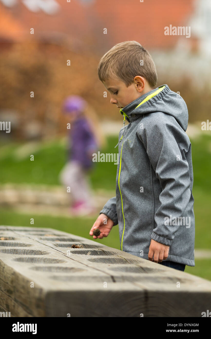 Boy counting at an wooden outdoors mancala game. Trademarks on jacket have been removed. Stock Photo