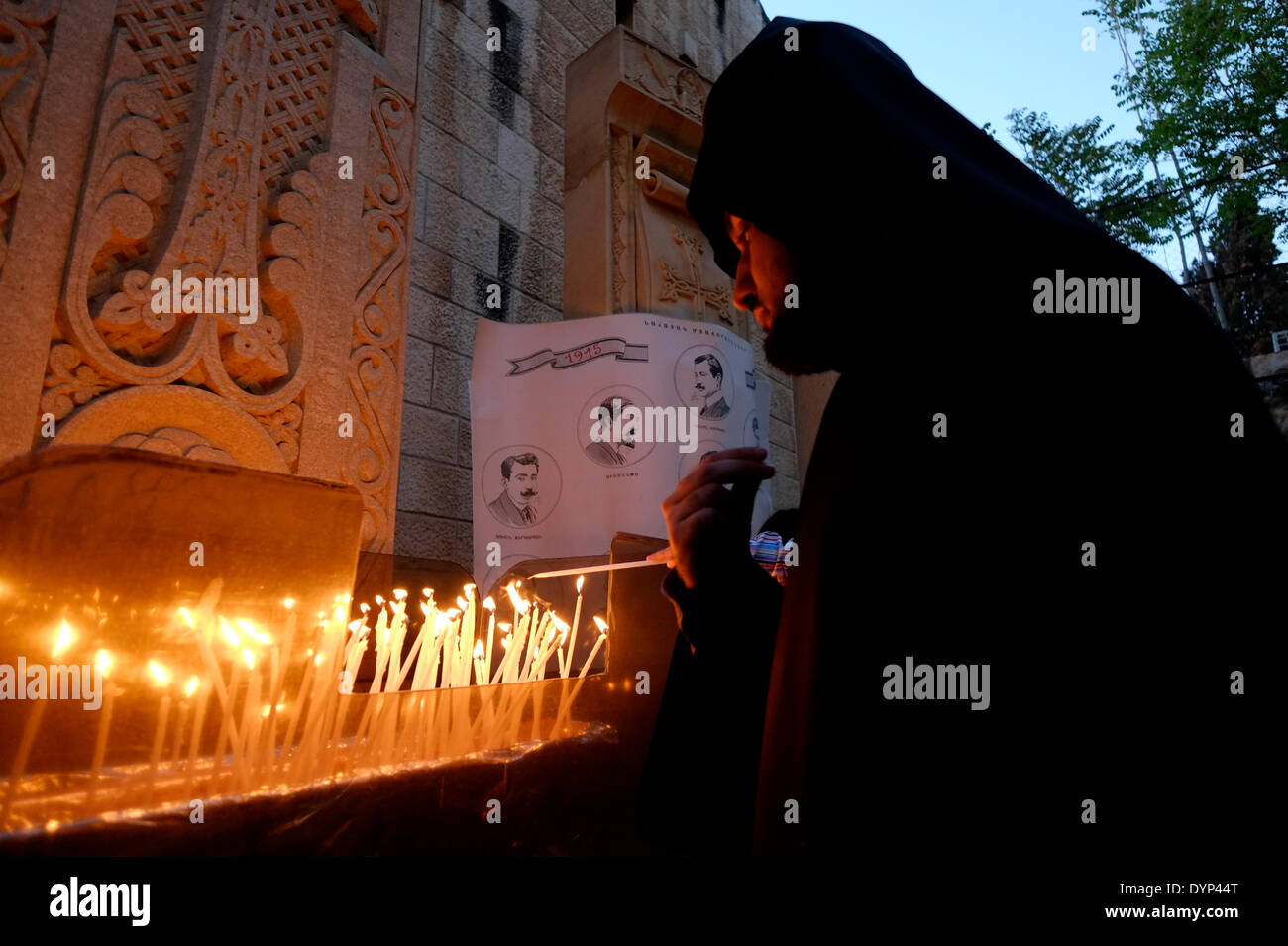 An Armenian priest lights candles at the Armenian Genocide memorial during commemoration ceremony of the 99th anniversary of the Armenian Genocide in the Armenian quarter Old city East Jerusalem Israel on 24  APRIL 2014. Genocide Remembrance Day or Genocide Memorial day, is observed by Armenians in dispersed communities around the world on April 24 . It is held annually to commemorate the victims of the Armenian Genocide from 1915 to 1923. Stock Photo