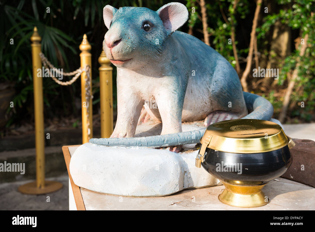 A cute rat sculpture, a Chinese zodiac animal sculpture at Wat Saket, Thai Temple, Thailand. A donation bowl sits beside him. Stock Photo