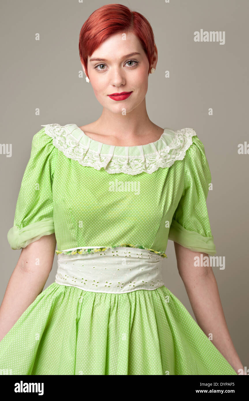 A red hair woman,Caucasian woman, female model wearing a babydoll 50s dress, posing in a studio, a 50s vintage fashion concept Stock Photo