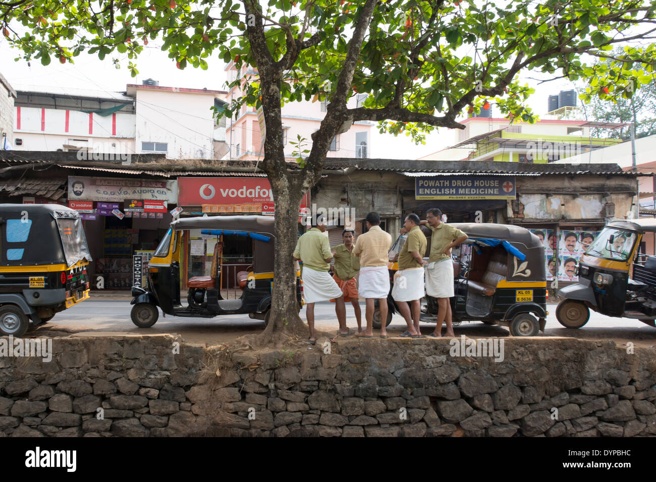 Auto Rickshaws and their drivers parked by a waterway in the backwaters of Kerala in India Stock Photo