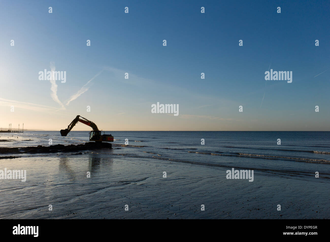 Backhoe digger on beach, low tide, sunrise, mechanical excavator Stock Photo