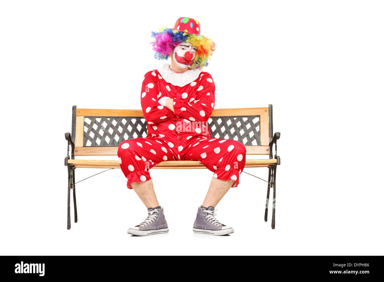 Unhappy clown sitting on a wooden bench Stock Photo