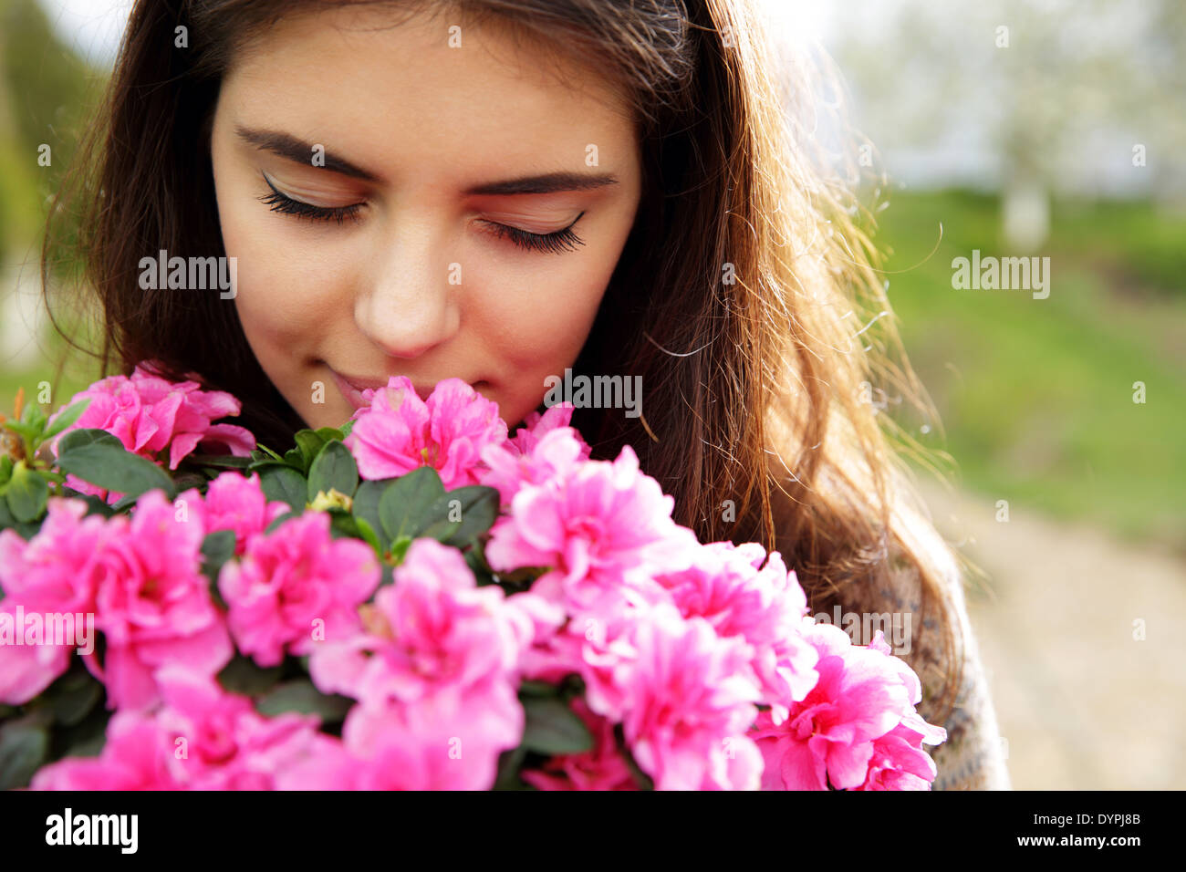 Portrait of a young woman smelling pink flowers Stock Photo - Alamy