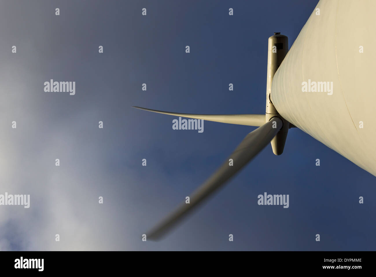 Wind turbine Blades from directly underneath showing movement with clouds and blue sky. Stock Photo