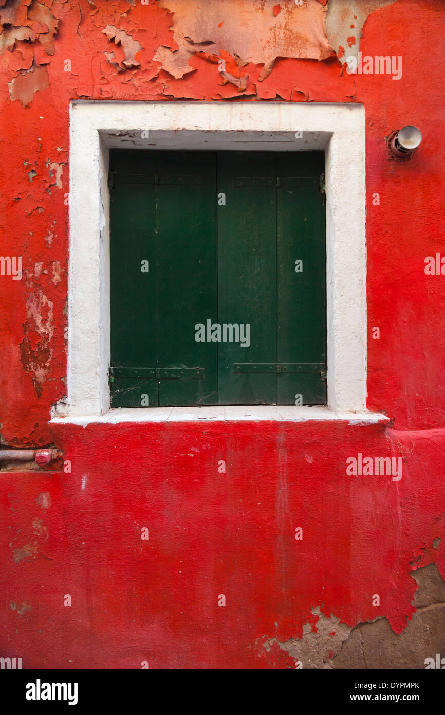 Vertical close up of window with green shutters on bright red wall, Venice Stock Photo