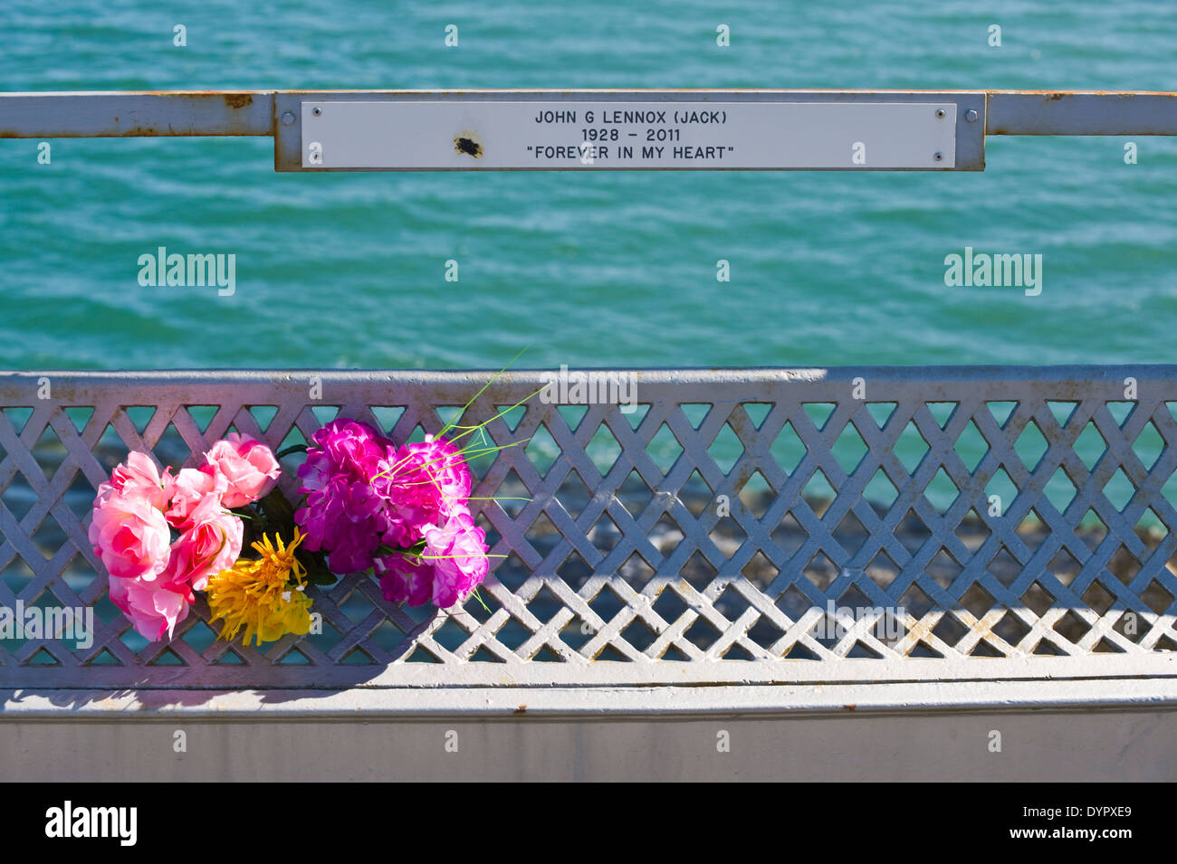 Memorial plaques with flowers on Bangor Pier on the Menai Strait at Bangor Gwynedd North Wales UK Stock Photo