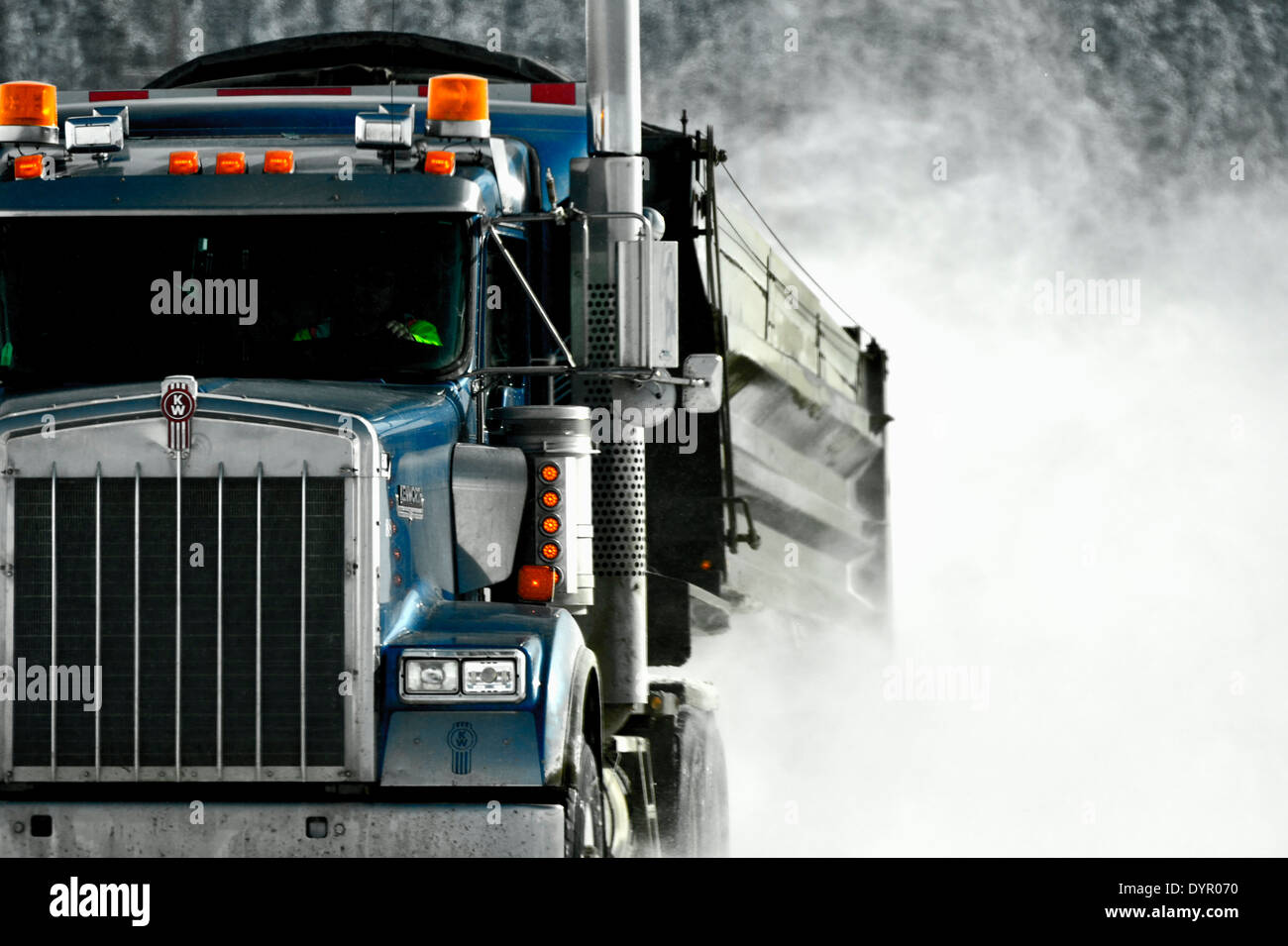 A semi truck hauling a dump trailer over a snow covered road Stock Photo