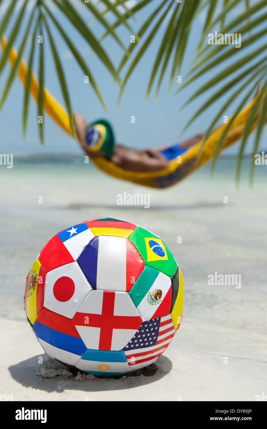 Brazilian man relaxing in beach hammock with international team flag football soccer ball Stock Photo