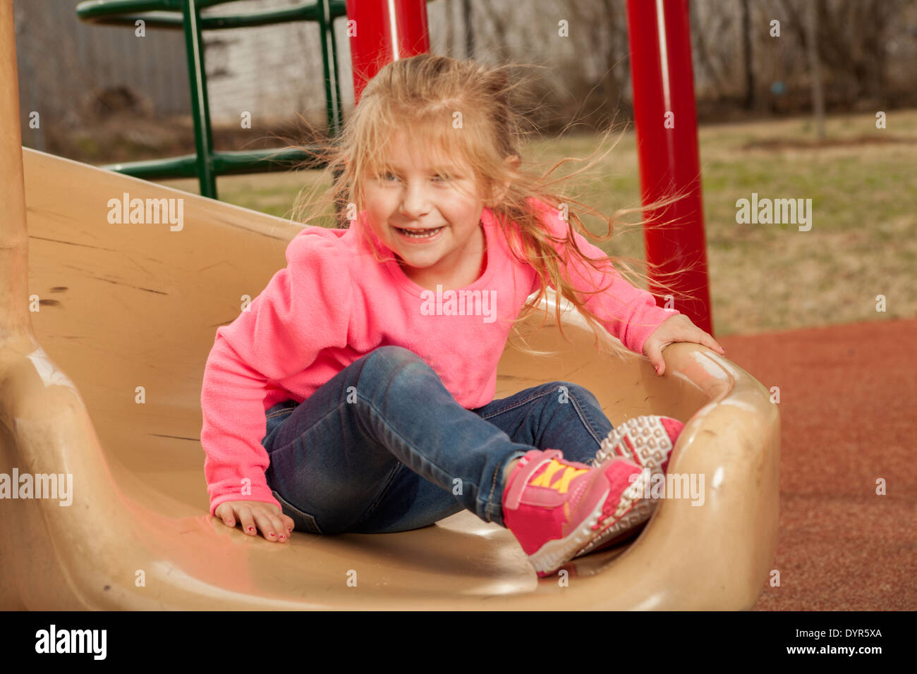Young girl at the park, playing on the slide Stock Photo - Alamy
