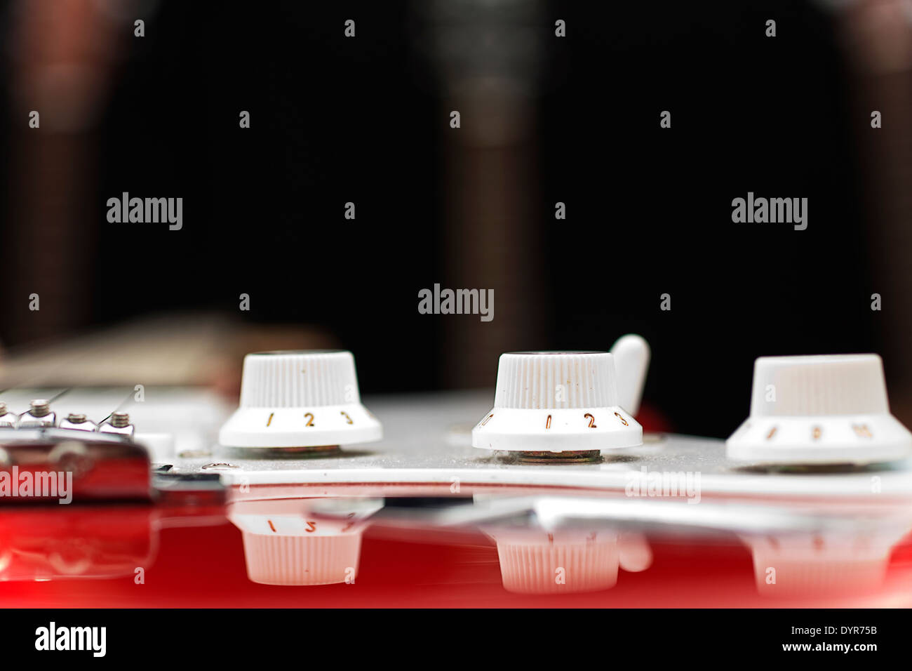 Side view of volume and tone controls on an electric guitar, with selective focus on the middle