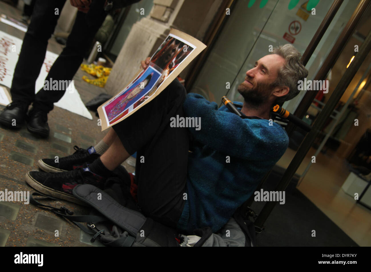 London, UK. 24th April 2014. A protester with his necked chained on the glass doors of the Oxford Street store. The protest began at 8.30am. Credit:  david mbiyu/Alamy Live News Stock Photo
