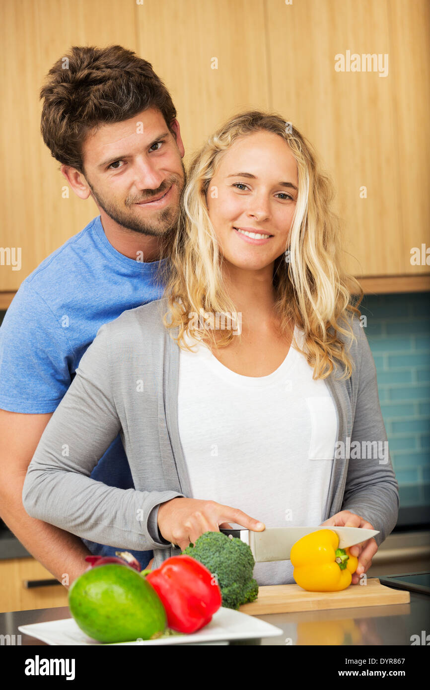 Happy young couple at home in the kitchen making dinner Stock Photo