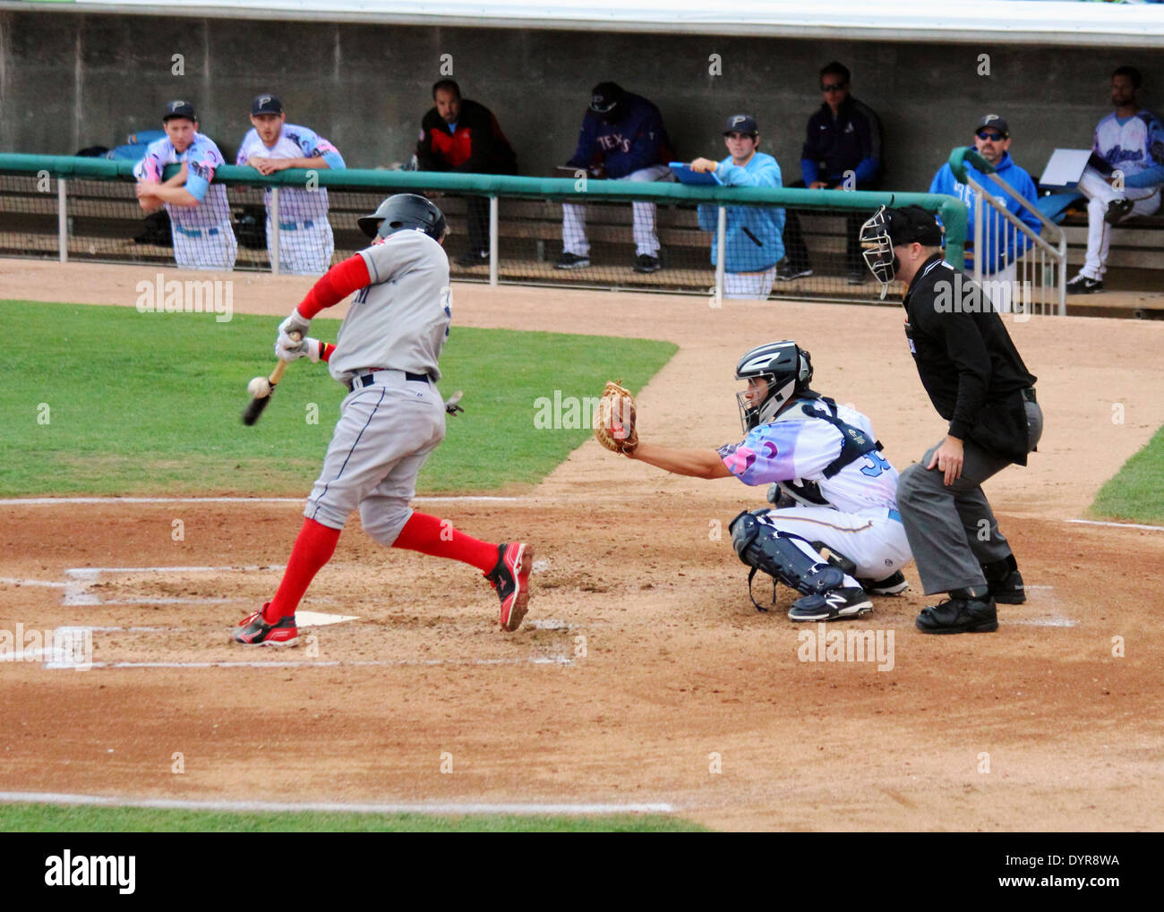 A batter swings and makes contact with the ball at homeplate. Stock Photo