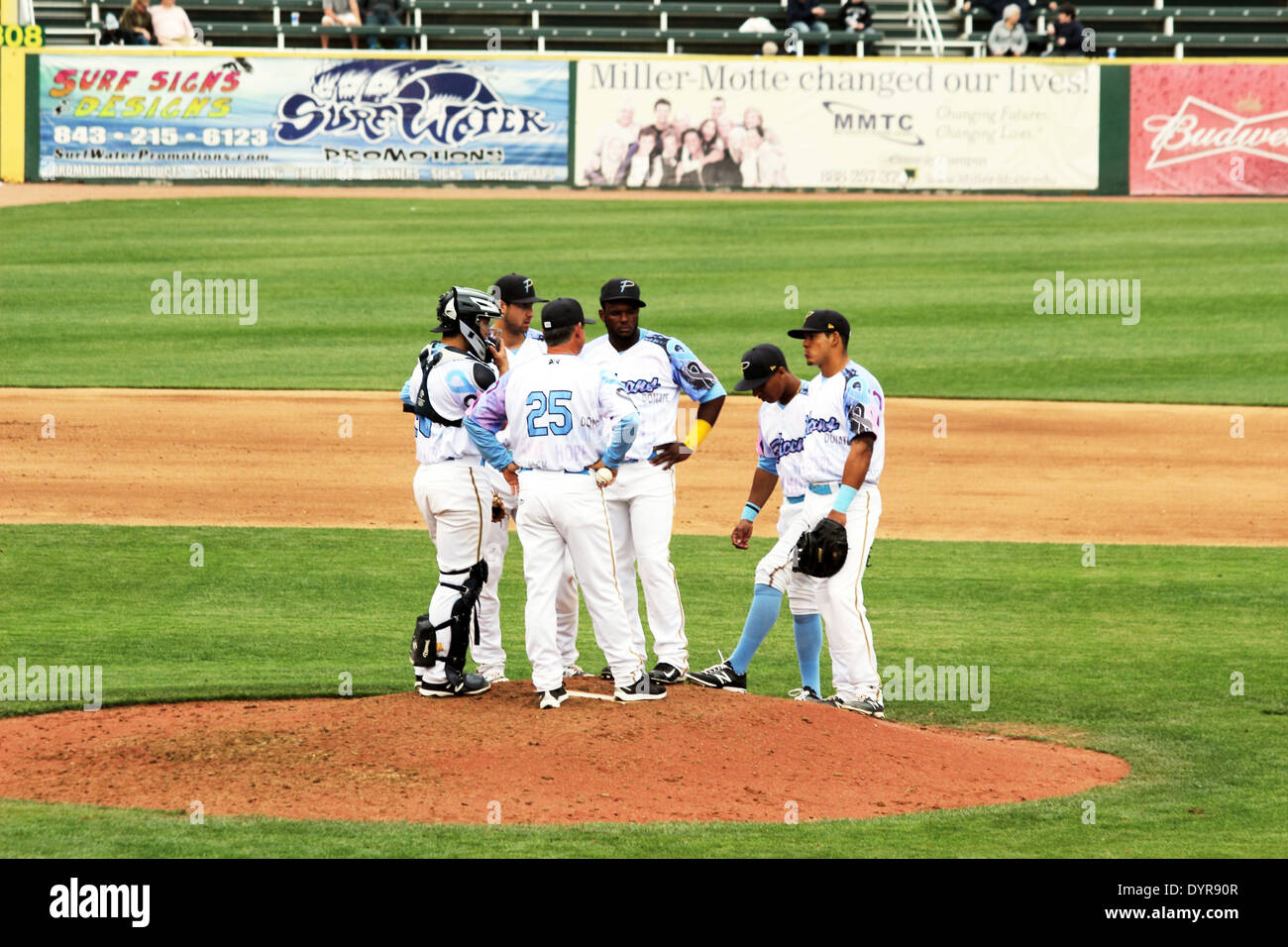 A baseball team converges on the pitchers mound to discuss strategy. Stock Photo