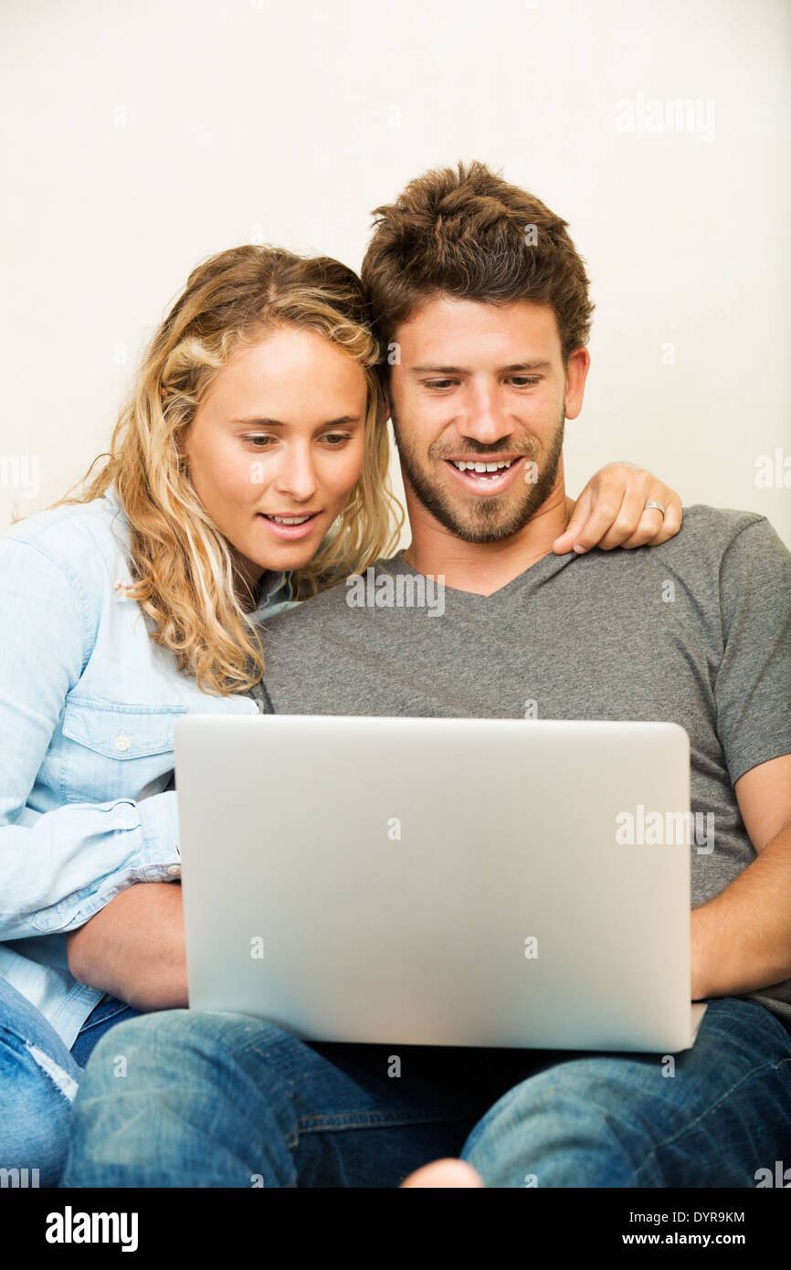 Happy young couple at home using laptop computer Stock Photo
