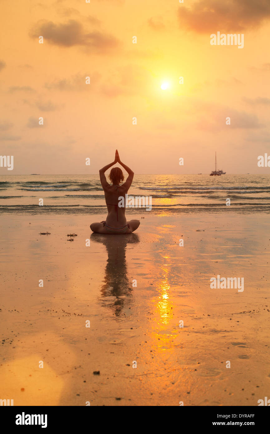 Silhouette young woman practicing yoga on the beach at sunset Stock ...