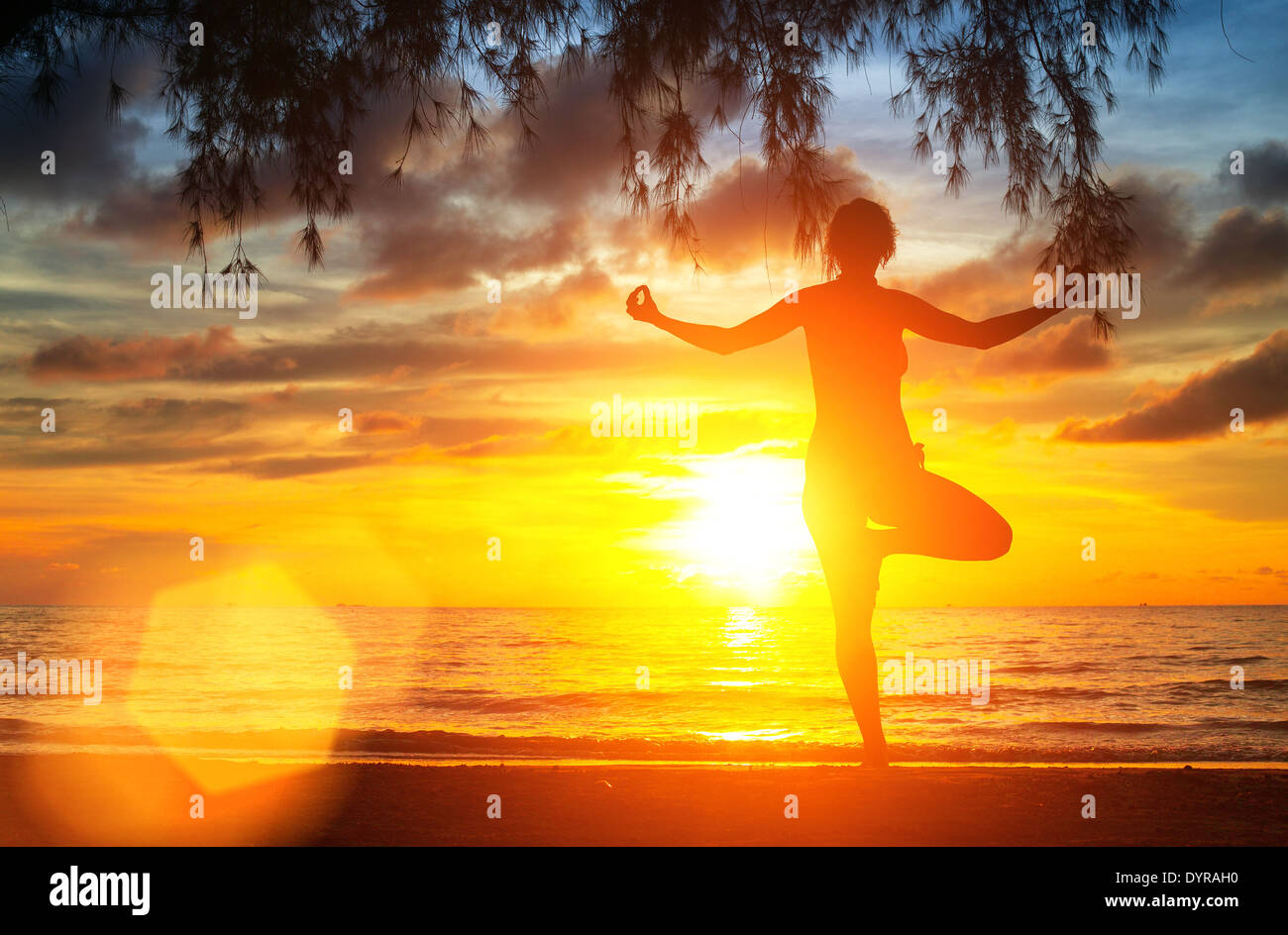 Yoga tree pose by woman silhouette with sunset sky background Stock
