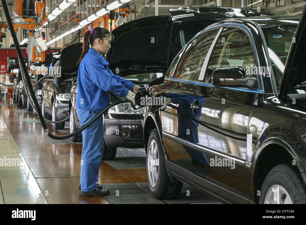 A worker fuels up a Volkswagen Passat at the end the production line at Shanghai Automotive Industries Corp Stock Photo