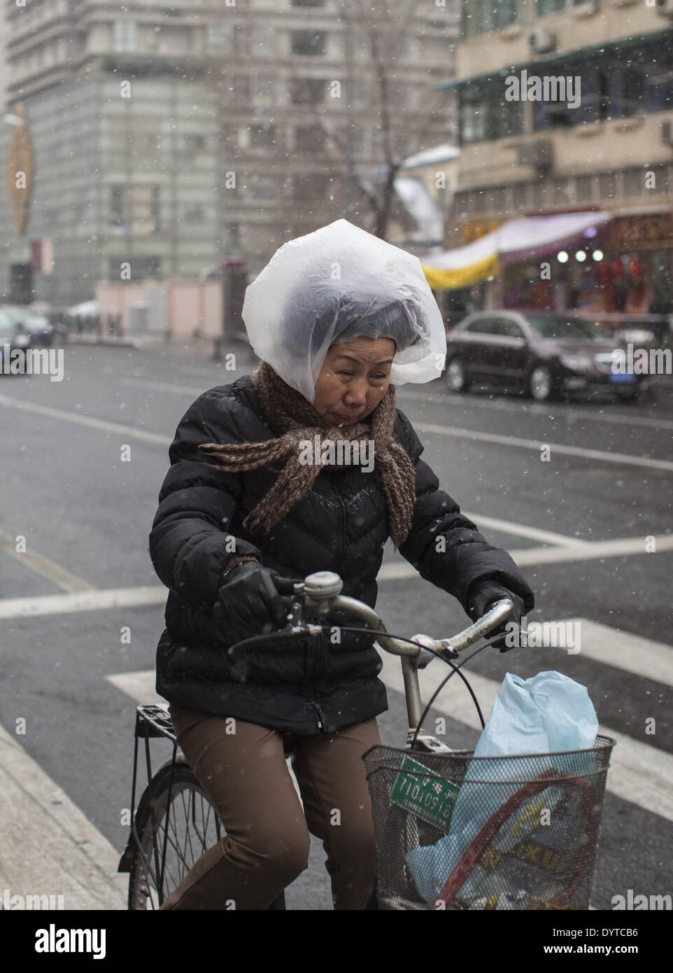 A woman uses a plastic bag to protect herself from snow Stock Photo